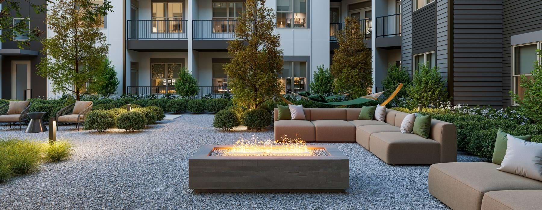 a courtyard with a few chairs and trees in front of a building with a fire pit