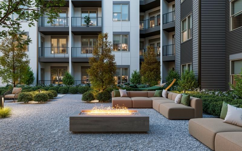 a courtyard with a few chairs and trees in front of a building with a fire pit